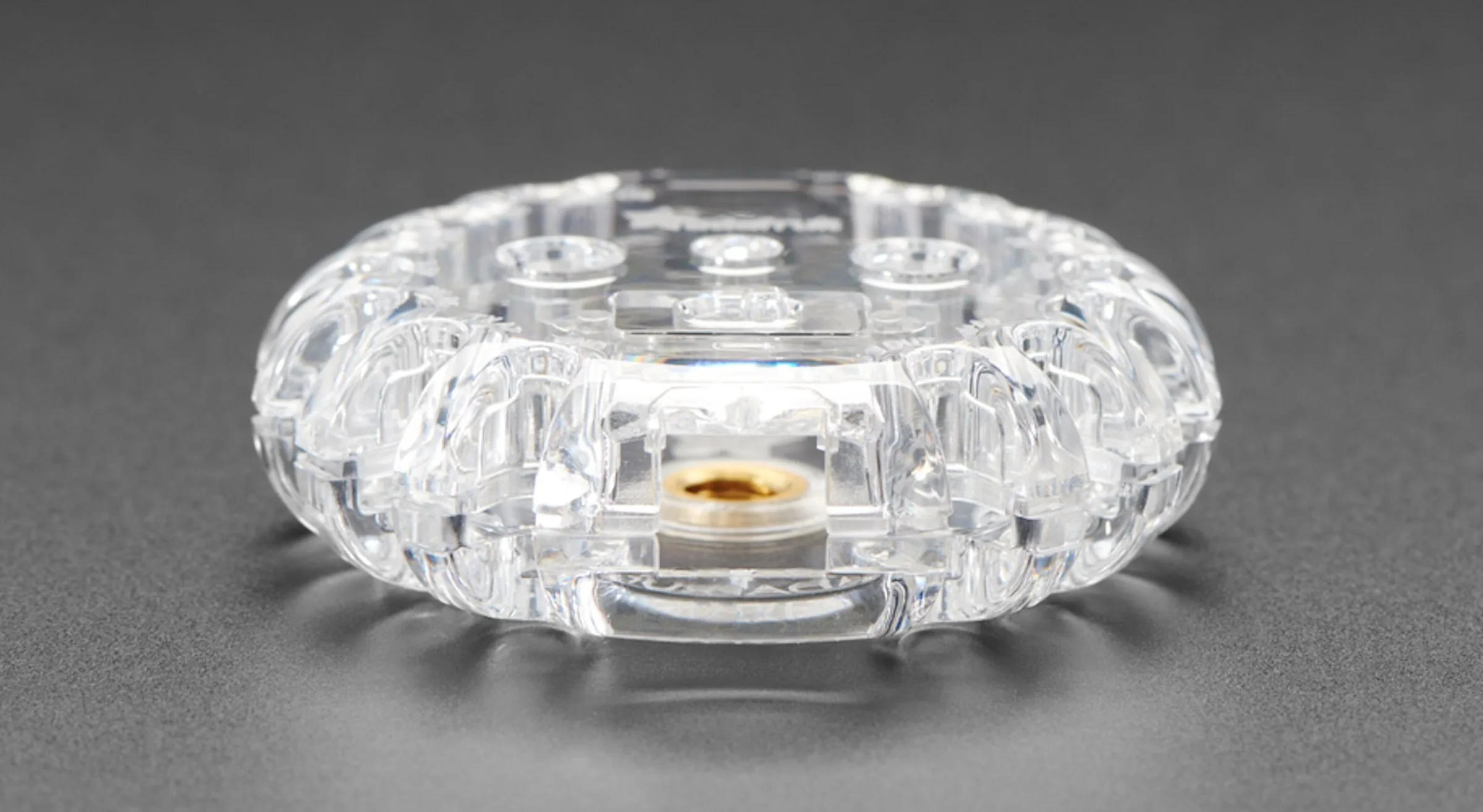 Clear Circuit Playground enclosure seen edge-on, showing the brass mounting insert