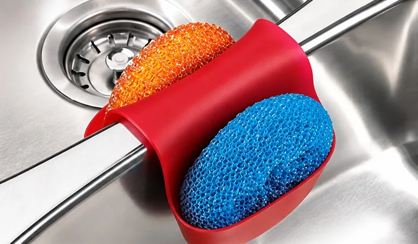 Red Sink Caddy straddling a sink divider, holding two scrubbers